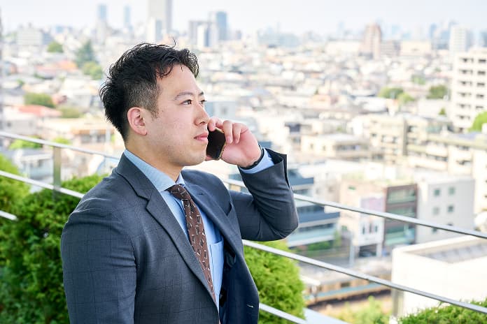 ビジネススーツ姿で電話対応する営業社員