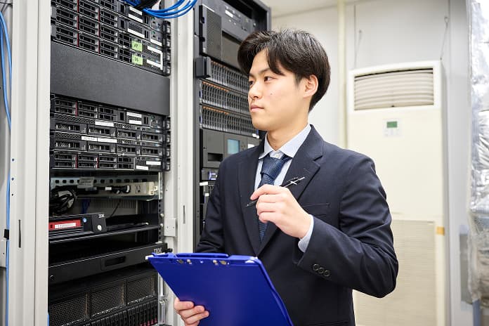 サーバールームで機器を点検するシステム開発社員