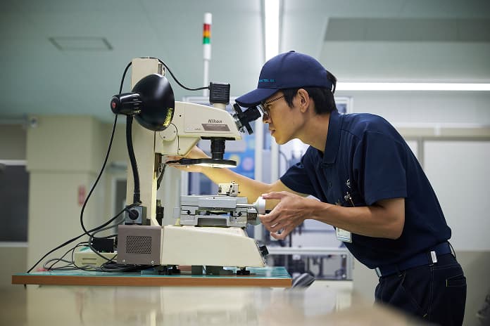 工業用顕微鏡で製品を検査する技術職社員